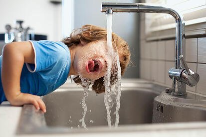 Child drinking water from faucet