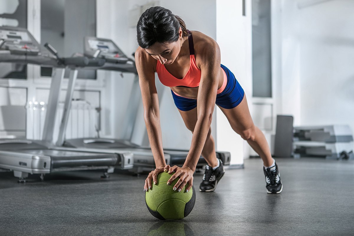 A woman doing a pushup with a medicine ball