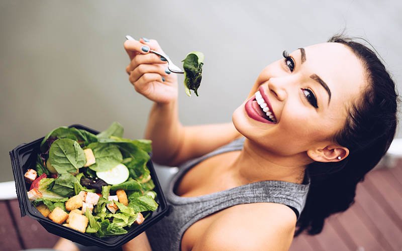 woman eating a salad full of leafy greens